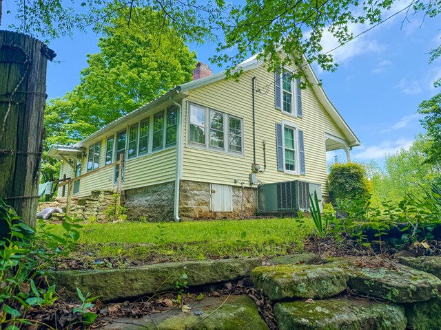 rear view of house featuring a chimney and central AC