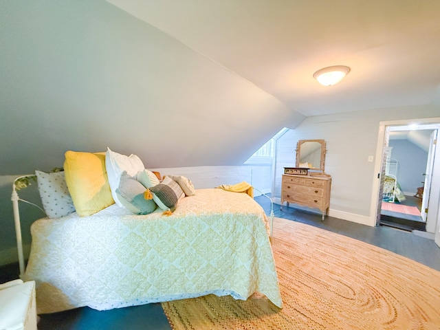 bedroom featuring baseboards, vaulted ceiling, and wood finished floors