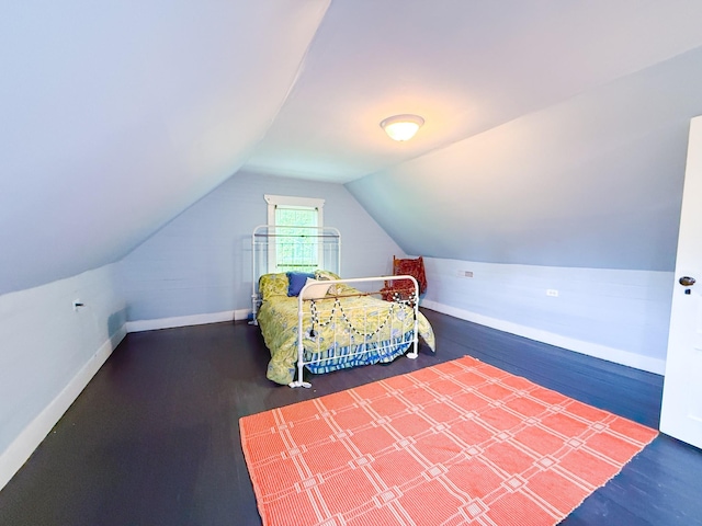 bedroom with baseboards, vaulted ceiling, and wood finished floors