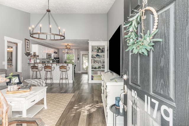 entrance foyer featuring an inviting chandelier, a textured ceiling, and dark wood finished floors