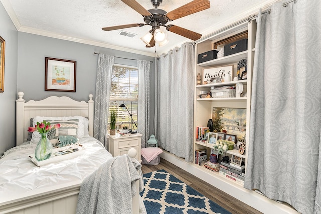 bedroom with ceiling fan, a textured ceiling, visible vents, crown molding, and wood finished floors