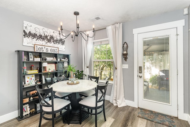 dining room with visible vents, an inviting chandelier, wood finished floors, baseboards, and a textured ceiling