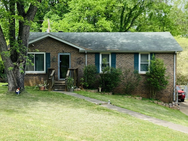 single story home with brick siding, a shingled roof, and a front yard