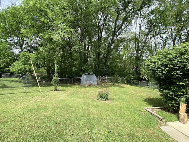 view of yard featuring a fenced backyard, a storage unit, and an outbuilding