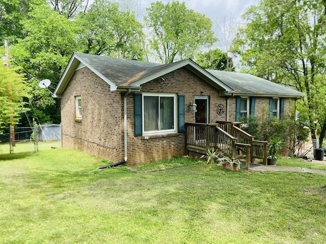 ranch-style house with fence, a front yard, roof with shingles, and brick siding