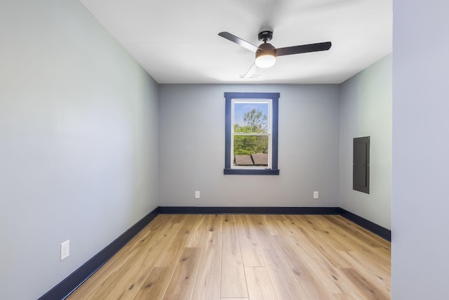 empty room featuring baseboards, ceiling fan, electric panel, and light wood-style flooring