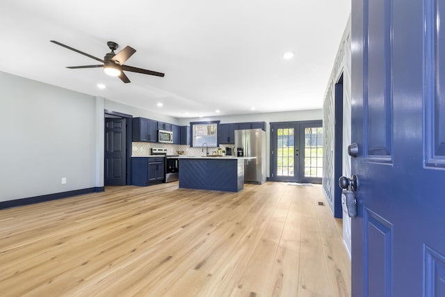 kitchen with appliances with stainless steel finishes, light countertops, blue cabinetry, recessed lighting, and backsplash
