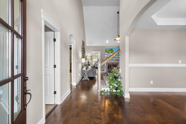 foyer entrance with arched walkways, stairway, baseboards, and a ceiling fan