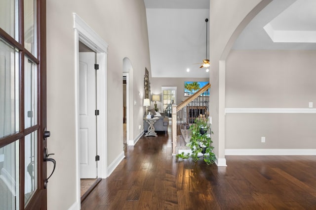 foyer with arched walkways, a ceiling fan, stairs, and wood finished floors