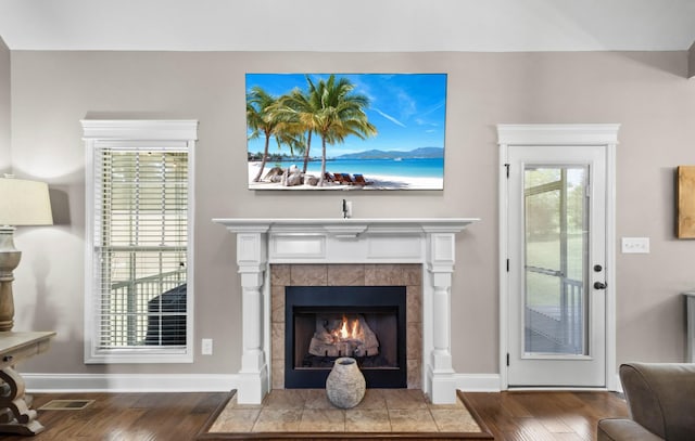 living room featuring wood finished floors, a tile fireplace, and baseboards