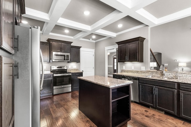 kitchen with stainless steel appliances, a sink, beamed ceiling, light stone countertops, and a kitchen island