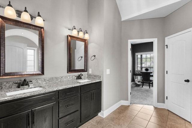 full bathroom with double vanity, tile patterned flooring, baseboards, and vaulted ceiling