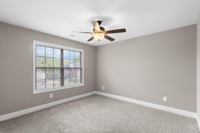 carpeted spare room with ceiling fan and baseboards