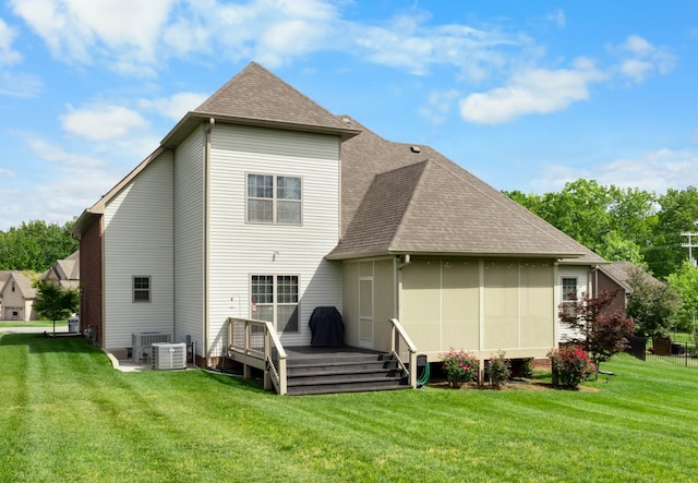 rear view of house with a deck, a shingled roof, and a yard