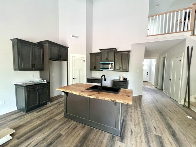 kitchen with a sink, visible vents, stainless steel microwave, and a towering ceiling