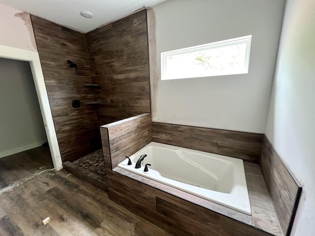 bathroom featuring a tile shower, wood finished floors, and a garden tub