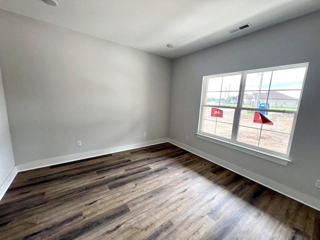 spare room with baseboards, dark wood-style flooring, and visible vents
