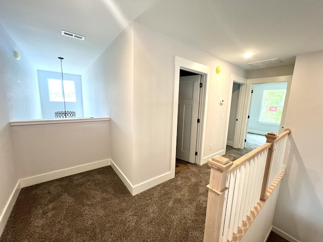 corridor featuring baseboards, visible vents, and plenty of natural light
