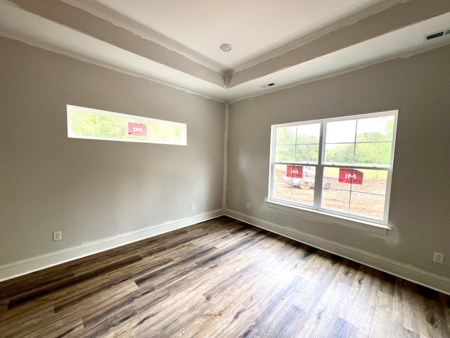 unfurnished room featuring a tray ceiling, visible vents, baseboards, and dark wood-type flooring