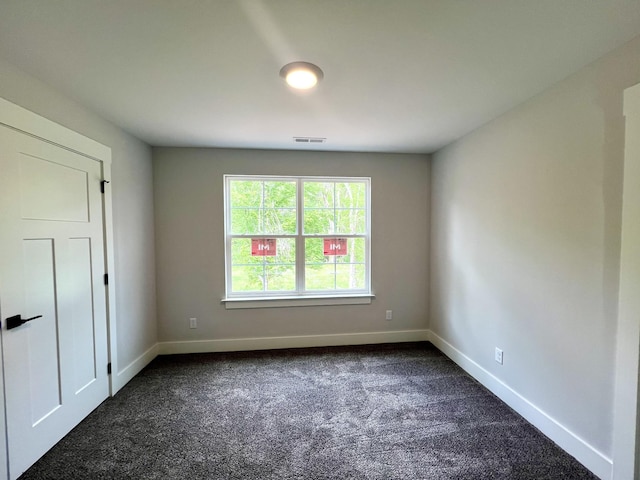 empty room featuring dark colored carpet, baseboards, and visible vents
