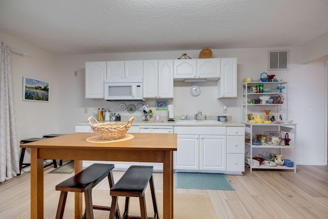 2510 Port Kembla Dr, Mount Juliet, TN 37122 - kitchen with visible vents, light wood-type flooring, a sink, white microwave, and white cabinetry