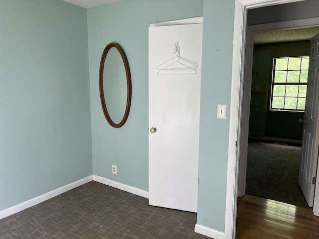unfurnished bedroom featuring baseboards and dark colored carpet