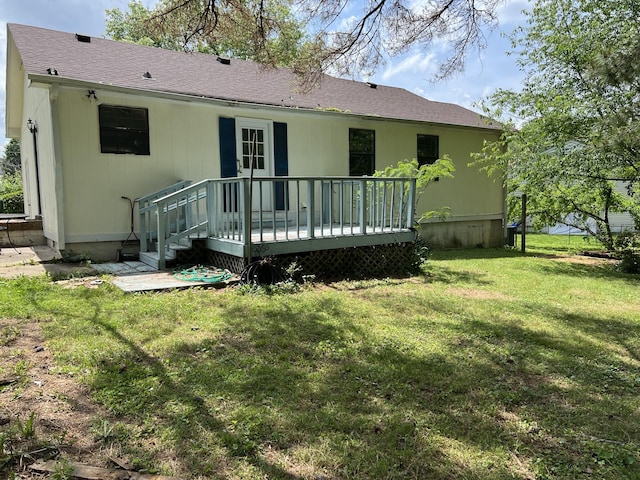 rear view of house with a yard, a wooden deck, and roof with shingles