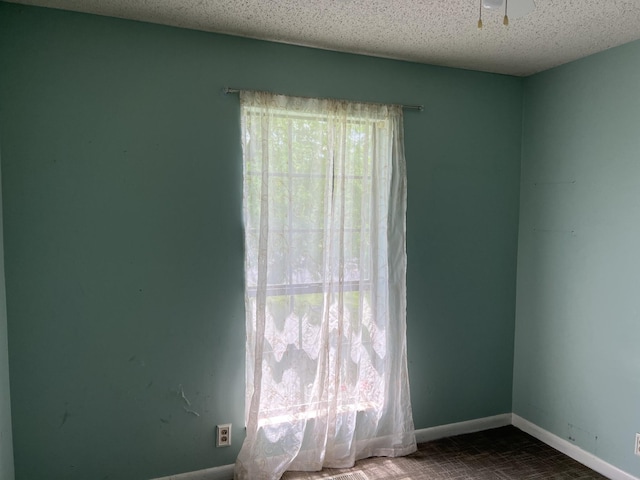 empty room with a textured ceiling and baseboards