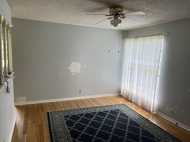 spare room with baseboards, a textured ceiling, ceiling fan, and wood finished floors