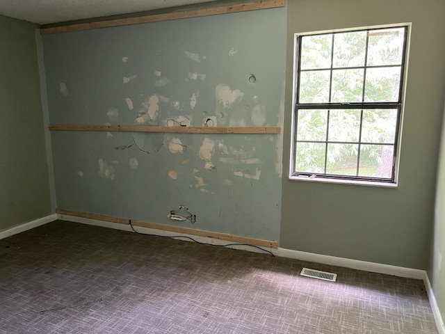 carpeted spare room with visible vents and baseboards