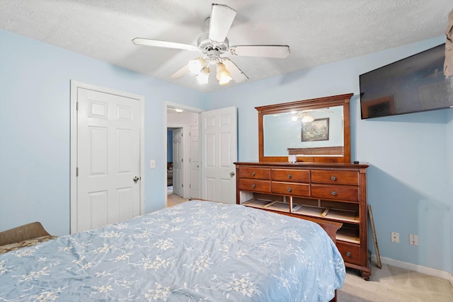bedroom featuring baseboards, ceiling fan, light carpet, and a textured ceiling
