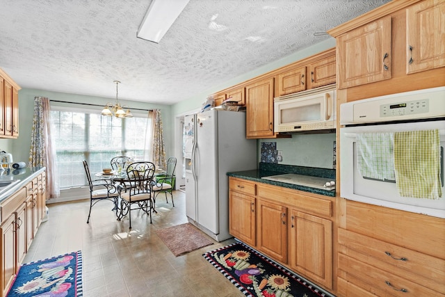 kitchen featuring white appliances, a textured ceiling, a notable chandelier, and dark countertops