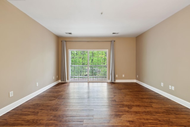 empty room featuring baseboards, visible vents, and dark wood-type flooring