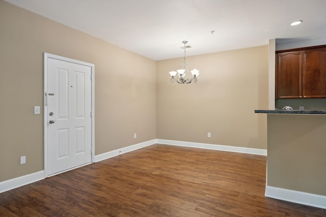 unfurnished dining area with recessed lighting, baseboards, dark wood finished floors, and an inviting chandelier