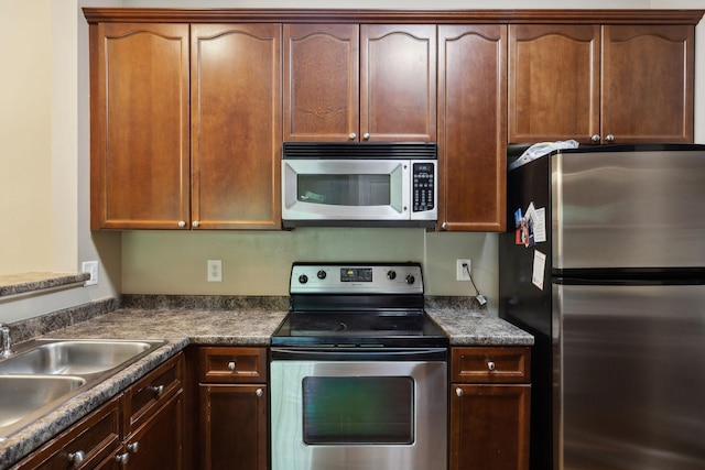 kitchen with stainless steel appliances, dark countertops, and a sink