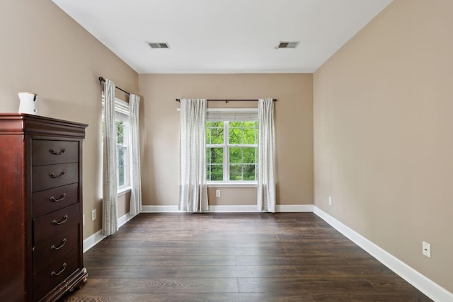 spare room featuring visible vents, dark wood-style flooring, and baseboards