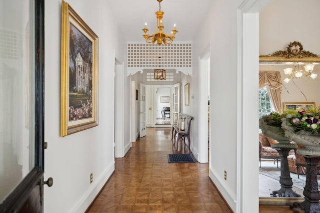 hall with baseboards and a chandelier