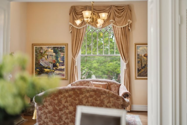 sitting room featuring baseboards, an inviting chandelier, and wood finished floors