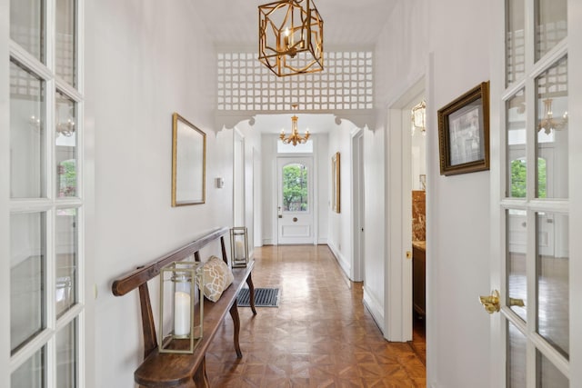 entryway featuring baseboards, a towering ceiling, and a chandelier
