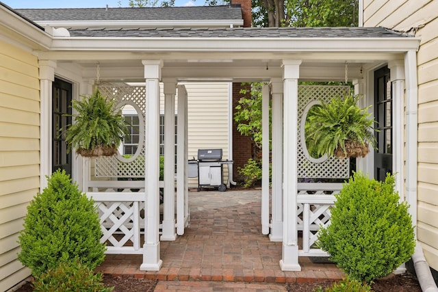 doorway to property featuring a porch and a shingled roof