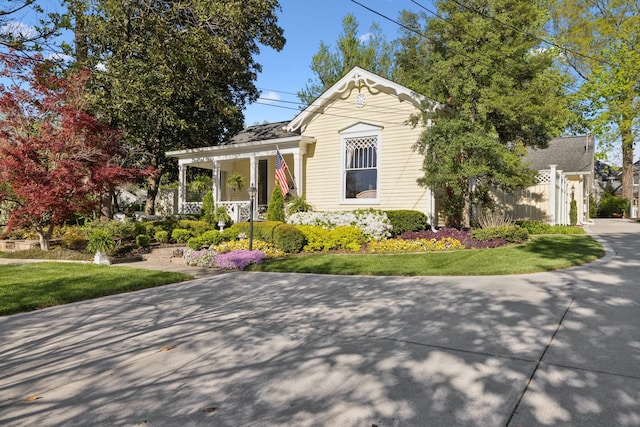 view of front of home with a front lawn, fence, and covered porch