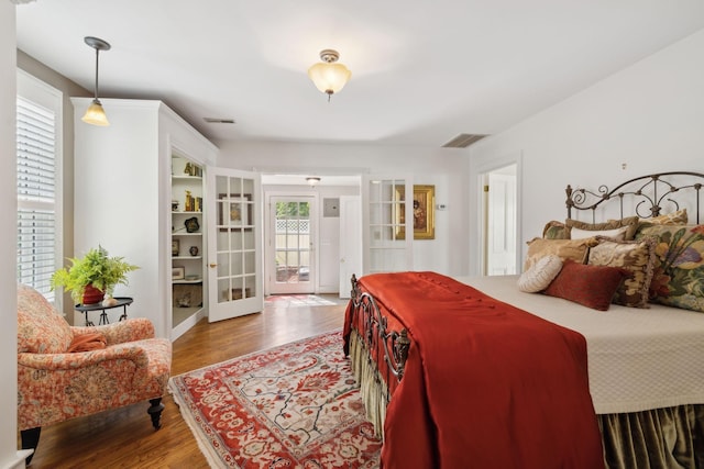 bedroom with visible vents, access to exterior, french doors, and wood finished floors