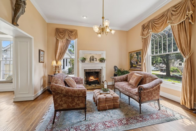 sitting room with crown molding, an inviting chandelier, a warm lit fireplace, and wood finished floors