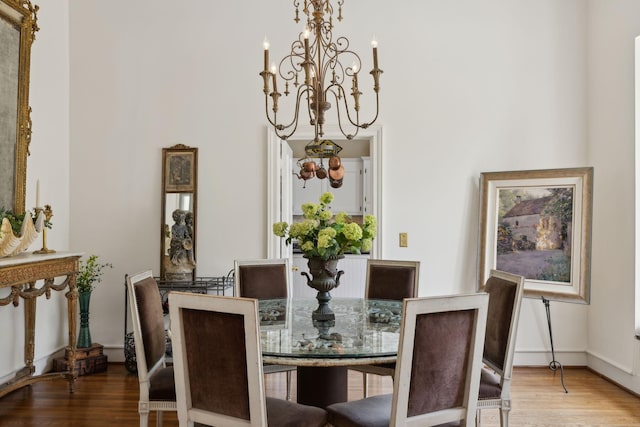 dining area with a towering ceiling, wood finished floors, and a chandelier
