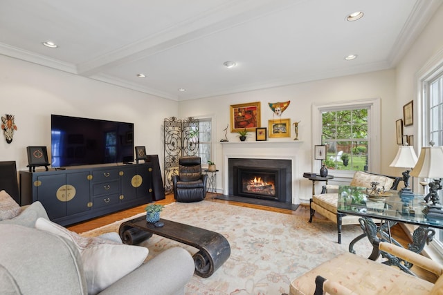 living room with ornamental molding, recessed lighting, wood finished floors, and a warm lit fireplace