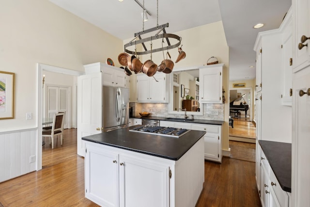 kitchen with dark countertops, appliances with stainless steel finishes, white cabinets, and a center island