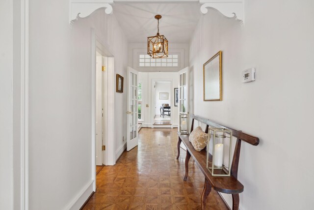 corridor featuring baseboards and a notable chandelier