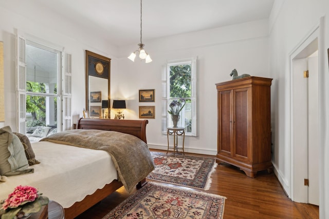 bedroom with baseboards, dark wood finished floors, and a chandelier