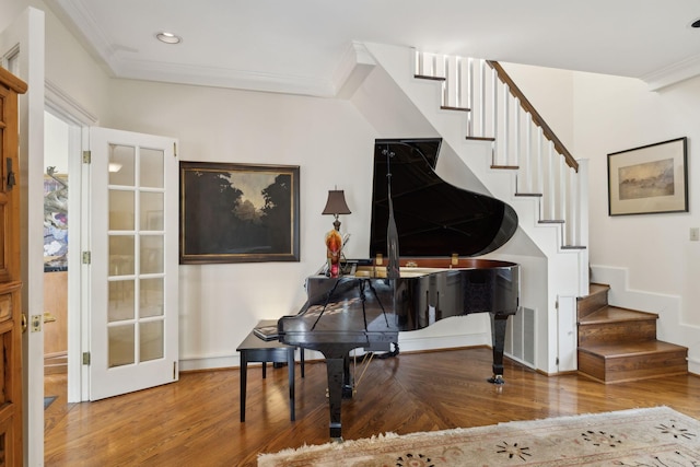 sitting room with ornamental molding, wood finished floors, and stairway