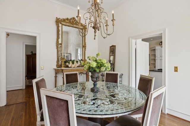 dining area with an inviting chandelier, baseboards, crown molding, and wood finished floors